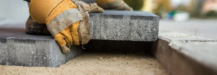 Person beim Verlegen von Pflastersteinen